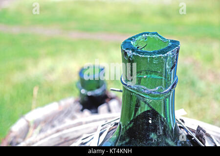 Vecchio vetro demijohn avvolto in vimini abbandonato Foto Stock