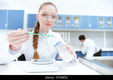 Giovane donna scienziato in occhiali protettivi lavora con il reagente di laboratorio Foto Stock