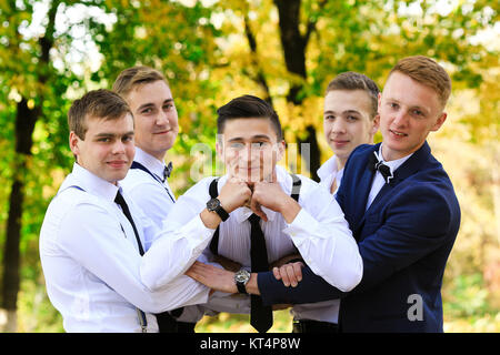 Gli uomini veri di amicizia. Gruppo di bello elegante uomini godendo del tempo insieme sul matrimonio di un loro amico. Sorridendo felice allegro gli uomini trascorrono del tempo insieme all'aperto in primavera, d'estate. I vecchi amici. Foto Stock