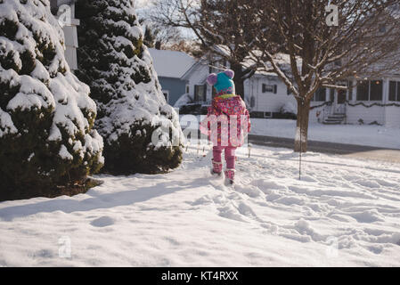 Un bambino bambina indossa un mantello colorato gioca nella neve. Foto Stock