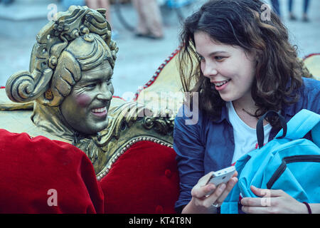 Bucarest, Romania - 29 Maggio 2014: l'uomo che agisce come Barocco ornamento del lettino presenta una gioiosa conversazione con una giovane donna mentre egli esegue il divano show. Foto Stock