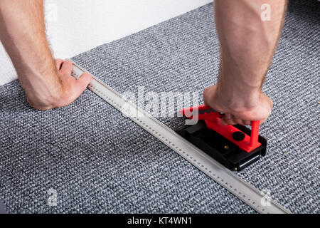 Artigiano con le mani in mano la posa di moquette Foto Stock