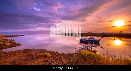 Nave da pesca nel fiume baia di ingresso sotto orange sunrise su Lesbo Island, Grecia Foto Stock