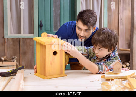 Concentrato di padre e figlio rendendo birdhouse in legno insieme in officina Foto Stock