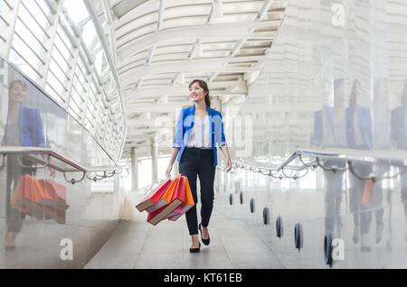 Giovane e bella asia donna con borse per lo shopping a piedi la strada a piedi. Foto Stock