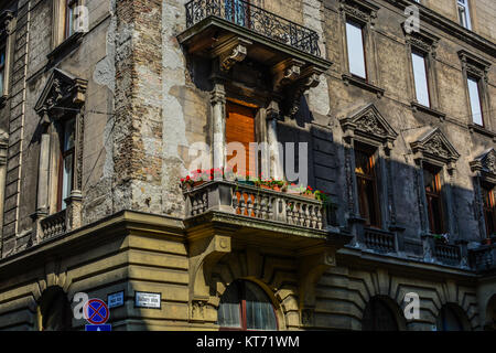 Un vecchio edificio di appartamenti in Bathory Utca in Parlamento area di Budapest Ungheria con muri cadenti e fiori di colore rosso sul balcone Foto Stock