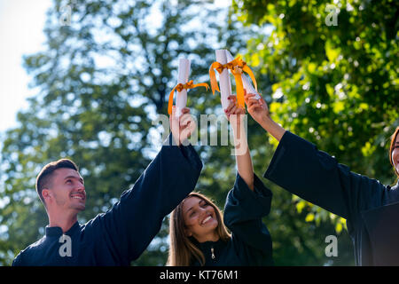 Istruzione, graduazione persone concetto - gruppo di felice gli studenti internazionali in mortaio e schede di corso di laurea gli abiti con diplomi Foto Stock