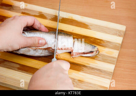 Mani femminili con Coltello per affettare il nasello pesce Foto Stock