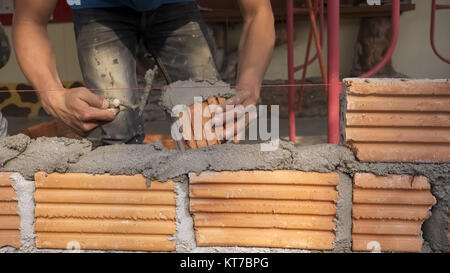 Muratore lavoratore installazione di muratura di mattoni sulla parete esterna Foto Stock