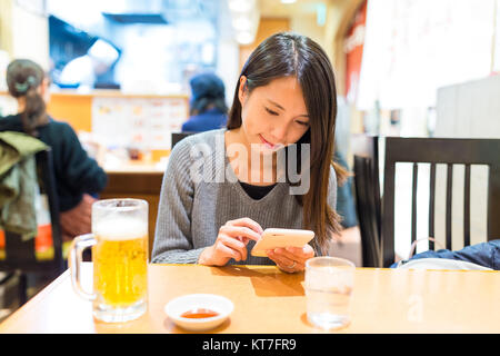 Donna uso del cellulare nel ristorante Foto Stock