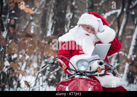 Babbo Natale su scooter utilizzando tablet Foto Stock