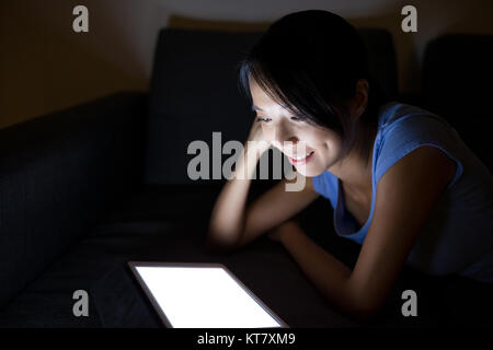 Donna che guarda la tavoletta digitale e sdraiato sul divano Foto Stock