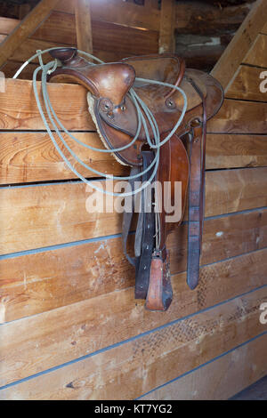 Sella occidentale con lariat sul muro della scuderia al Bar U Ranch National Historic Site, Alberta, Canada Foto Stock