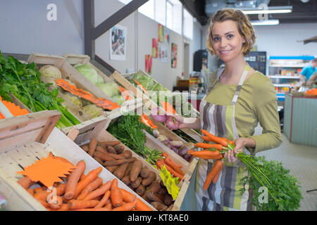 Lavoratore di sesso femminile che la vendita di frutta e ortaggi freschi sul mercato Foto Stock