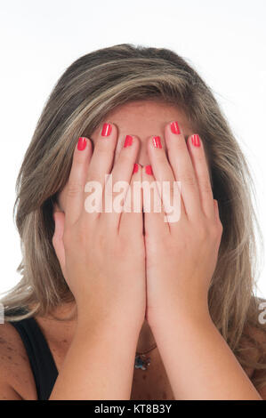 Giovane donna bionda nascondendo facew con le mani contro uno sfondo bianco Foto Stock