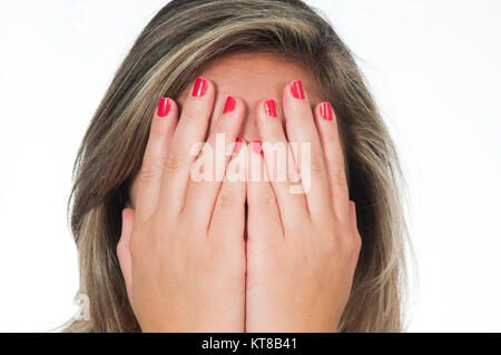 Giovane donna bionda nascondendo facew con le mani contro uno sfondo bianco Foto Stock