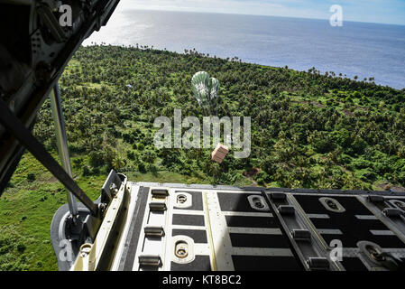 Un pacchetto con beni donati sospesi da un paracadute cade da una C-130J Super Hercules durante il funzionamento caduta di Natale dic. 11, 2017 sopra l'isola di Fais. Caduta di Natale è la più lunga del mondo in funzione airdrop missione. Per il terzo anno di fila, U.S., il giapponese e il personale di volo australiano addestrato a fianco di ogni altro mentre la fornitura di materiali di consumo critico di 56 isole della Micronesia incidono circa 20.000 persone e copre 1,8 milioni di mq miglia nautiche di area operativa. Il C-130 è assegnato alla XXXVI Airlift Squadron a Yokota Air Base, Giappone. (U.S. Air Force Foto Stock