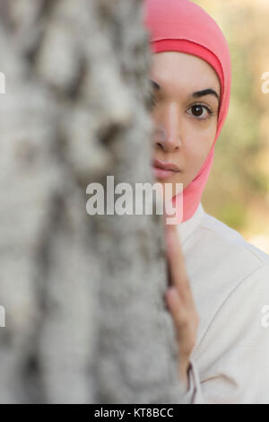 Donna musulmana nascondersi dietro a un albero Foto Stock