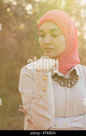 Preoccupato donna musulmana in piedi all'aperto mano toccando il mento Foto Stock
