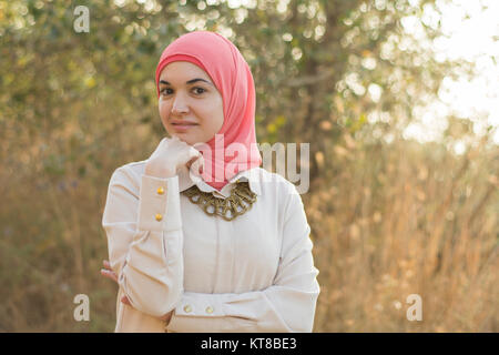 Bella donna musulmana toccando a mano mento sorridere all'aperto Foto Stock