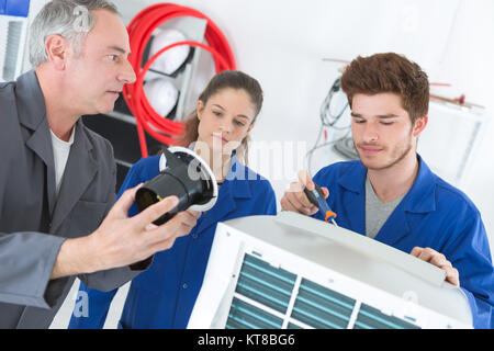 Insegnante osservando gli studenti che lavorano su apparecchio elettrico Foto Stock