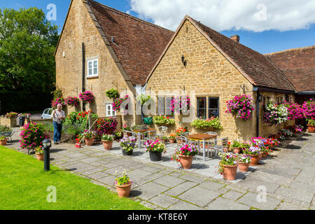 Il magnifico e motivi floreali colorati nei cestini appesi e vasche fuori il Rose and Crown Inn a East Lambrook, Somerset, Inghilterra, Regno Unito Foto Stock