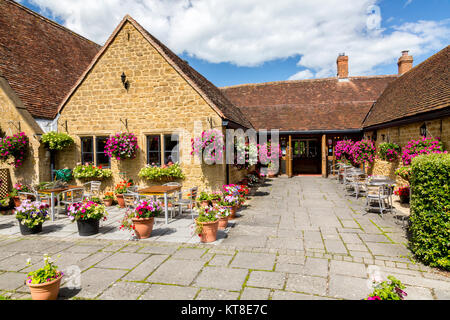 Il magnifico e motivi floreali colorati nei cestini appesi e vasche fuori il Rose and Crown Inn a East Lambrook, Somerset, Inghilterra, Regno Unito Foto Stock