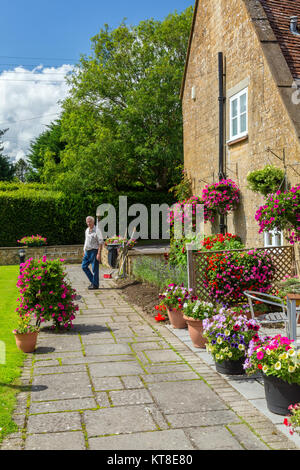 Il magnifico e motivi floreali colorati nei cestini appesi e vasche fuori il Rose and Crown Inn a East Lambrook, Somerset, Inghilterra, Regno Unito Foto Stock