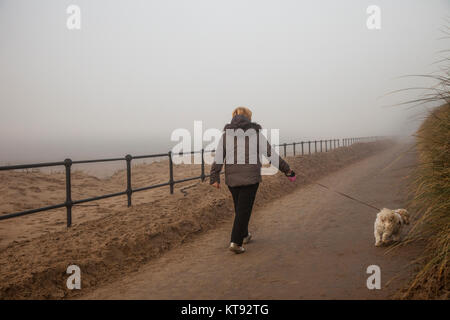 Crosby, Merseyside. Regno Unito Meteo. Il 23 dicembre, 2017. Mild & Misty, nebbia, per iniziare la giornata con una vasta nebbia di mare sulla costa di Sefton. Le miti condizioni per incoraggiare la gente a godere la Crosby sentiero costiero su Mariners modo. Di avvezione nebbia - è chiamato anche mare nebbia, quando circola aria calda sopra relativamente fredda la superficie del mare, ma è altrettanto comune su terra. Di avvezione nebbia è spesso associata con il passaggio di fronti freddi e caldi oltre la terra e il mare, è l'umida, drizzly roba che può rovinare quello che altrimenti sarebbe un bel giorno. Credito: MediaWorldImages/Alamy Live News Foto Stock