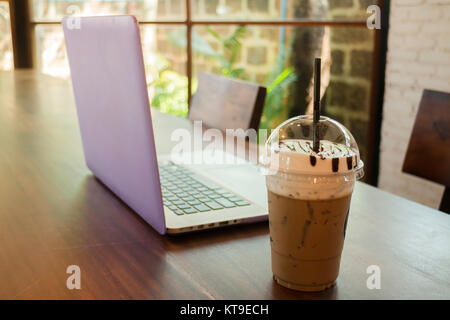 Sul computer portatile sul tavolo di legno al Coffee Shop Foto Stock