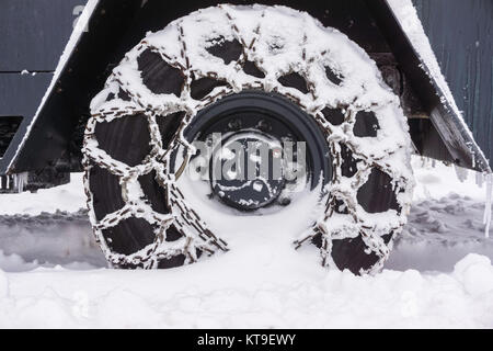 Close-up di un snowy incatenati ruota di un aratro di neve in inverno Foto Stock