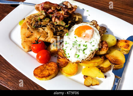 schnitzel con uova fritte, pancetta e patate fritte Foto Stock