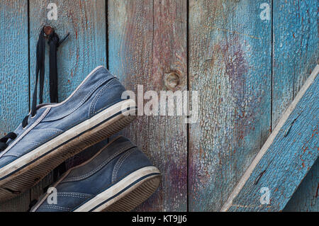 Coppia di vecchi e sporchi blu usurati sneakers appendere su un chiodo Foto Stock