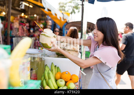 Donna acquisto drink di cocco nel mercato del weekend Foto Stock