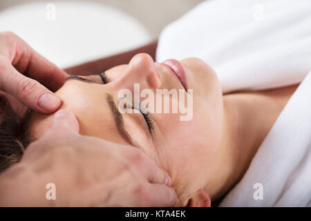 Terapeuta dando massaggio sulla donna di fronte Foto Stock