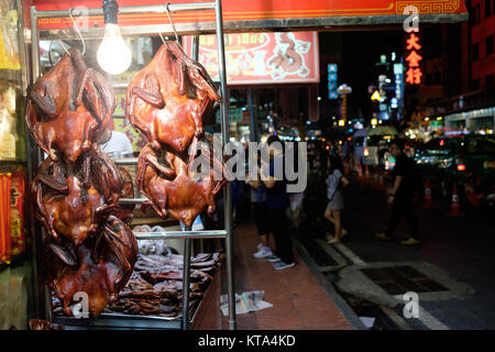 Croccante anatra per vendita a Bangkok Chinatown, sulla strada Yaorawat. Insegne al neon e turisti in background. Foto Stock