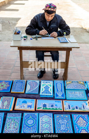 Un artista pittura a mano piastrelle a vendere il Bibi Khanym moschea, Samarcanda, Uzbekistan Foto Stock