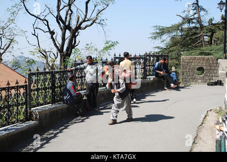 Un uomo che trasportava un carico pesante sulla sua schiena attraverso le strade di Shimla. Foto Stock