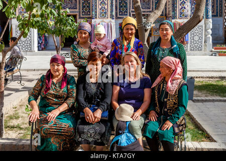 Un turista europeo in posa per una fotografia con locale donne uzbeke, Il Registan, Samarcanda, Uzbekistan Foto Stock