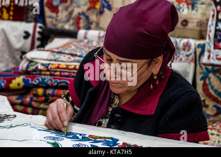 Una donna uzbeka producendo un suzani (Ricamo Classico), Ulugh Beg Madrassa, Il Registan, Samarcanda, Uzbekistan Foto Stock