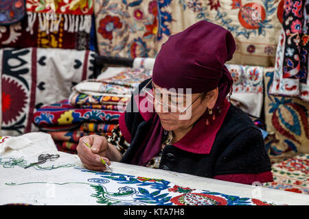 Una donna uzbeka producendo un suzani (Ricamo Classico), Ulugh Beg Madrassa, Il Registan, Samarcanda, Uzbekistan Foto Stock