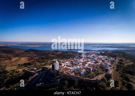 Vista aerea del villaggio storico di Monsaraz in Alentejo con la diga di Alqueva serbatoio sullo sfondo; concetto per il viaggio in Portogallo e Alent Foto Stock
