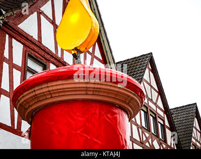 Enorme red christmas candle di fronte Hessian semi-case con travi di legno in un piccolo villaggio Foto Stock