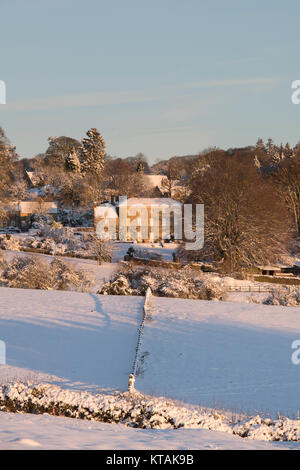 Bourton sulla collina casa padronale nella neve a sunrise in dicembre. Bourton sulla collina, Cotswolds, Gloucestershire, Inghilterra. Foto Stock