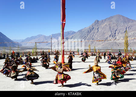 I monaci buddisti esegue il ballo mascherato a cerimonia religiosa, montagne panoramiche nel retro, Diskit Monastero, Valle di Nubra, Ladakh, Jammu e Kashmir India Foto Stock