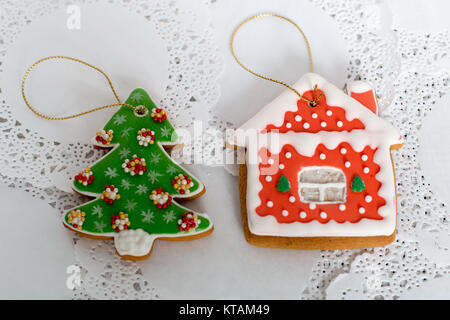 Due gingerbread cookies a forma di albero di Natale e la piccola casa su un tovagliolo bianco sullo sfondo. Vista superiore, piana, laici spazio copia Foto Stock