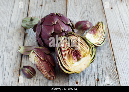 Carciofi romani su una tavola di legno Foto Stock