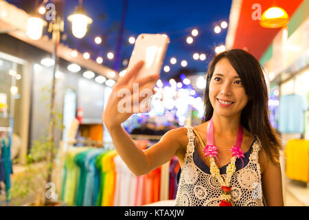 Giovane donna prendendo selfie dal cellulare al mercato notturno in Thailandia Foto Stock