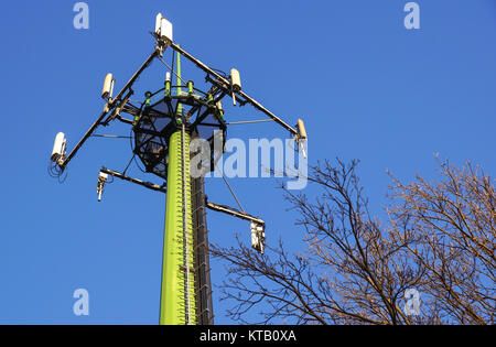 Acciaio torre di telecomunicazione con le antenne sul cielo blu e alberi Foto Stock