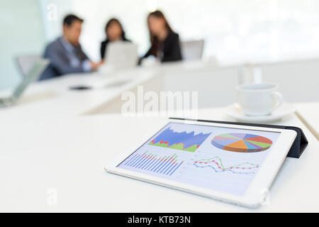 Tavoletta digitale che mostra il grafico con i partner aziendali a discutere in sala riunioni Foto Stock
